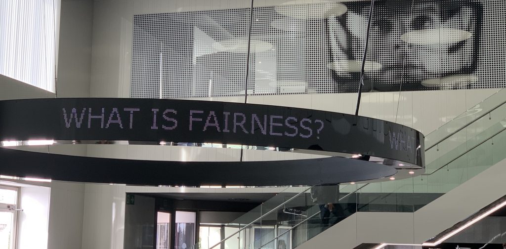 Image of digital sign reading "what is fairness?"